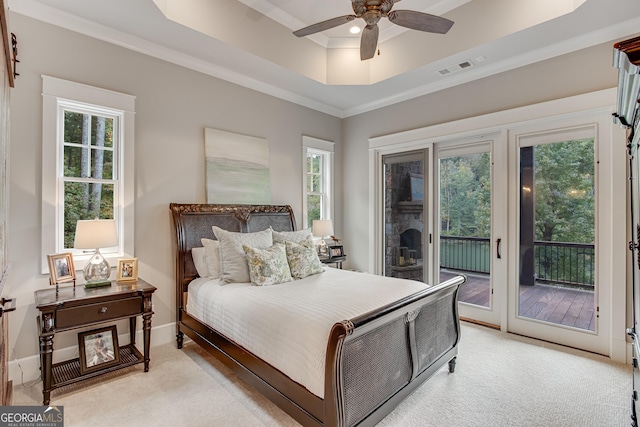 bedroom featuring multiple windows, light carpet, a raised ceiling, and access to exterior