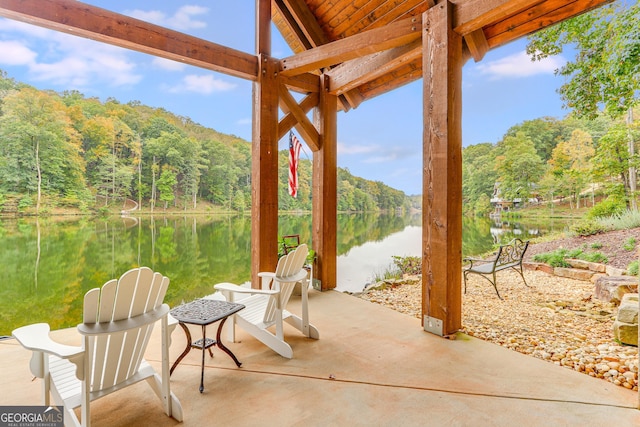 view of patio / terrace featuring a view of trees and a water view