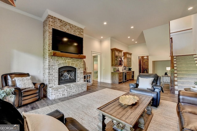 676 N Shore Dr, Cleveland, GA 30528 - living room featuring crown molding, light wood finished floors, stairs, a brick fireplace, and recessed lighting