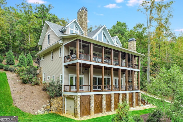 back of house with a shingled roof, a chimney, ceiling fan, and a balcony