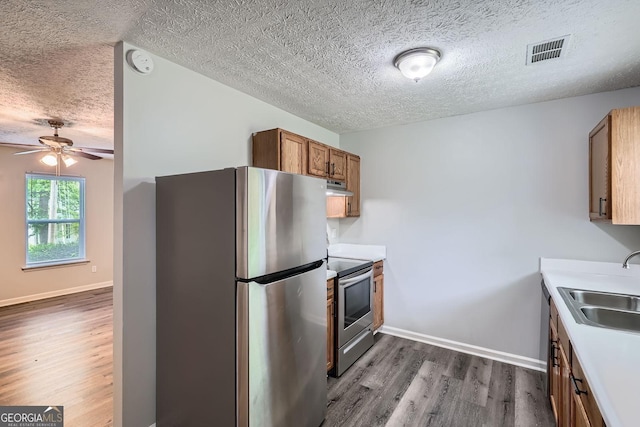7112 Greenway Cv SW, Covington, GA 30014 - kitchen featuring brown cabinetry, a textured ceiling, visible vents, appliances with stainless steel finishes, and dark wood-type flooring