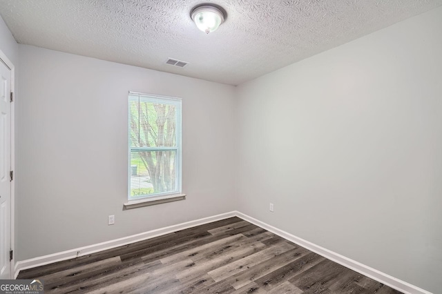 7112 Greenway Cv SW, Covington, GA 30014 - empty room with a textured ceiling, visible vents, baseboards, and dark wood-type flooring
