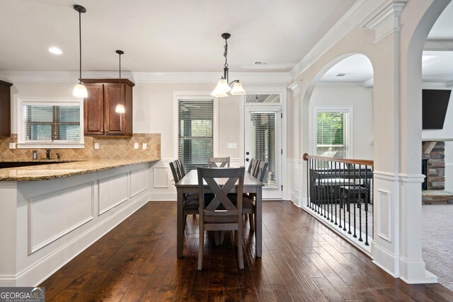 1314 Bentley Estates Dr, Dacula, GA 30019 - dining area with arched walkways, dark wood-style floors, crown molding, a decorative wall, and a wainscoted wall