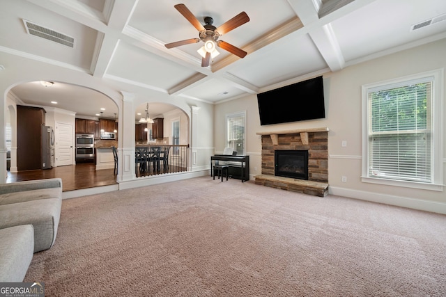 1314 Bentley Estates Dr, Dacula, GA 30019 - carpeted living room with arched walkways, a stone fireplace, plenty of natural light, coffered ceiling, and a ceiling fan
