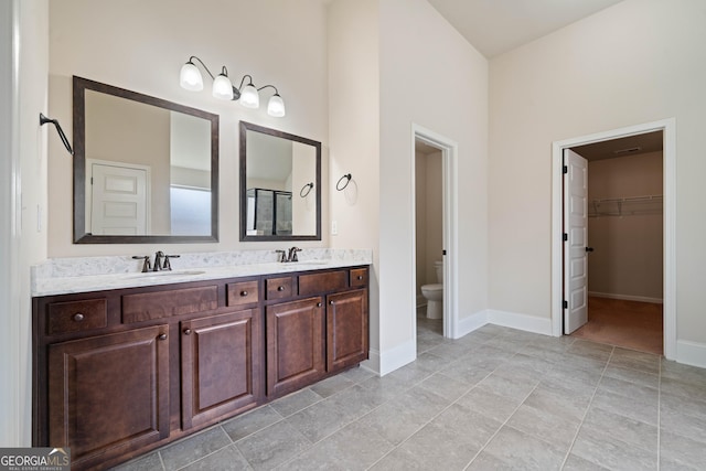 1314 Bentley Estates Dr, Dacula, GA 30019 - bathroom featuring toilet, double vanity, baseboards, and a walk in closet