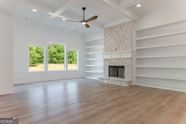 4731 H D Atha Rd, Covington, GA 30014 - unfurnished living room featuring a ceiling fan, wood finished floors, a stone fireplace, coffered ceiling, and built in shelves
