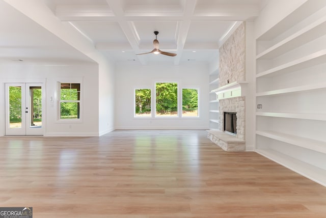 4731 H D Atha Rd, Covington, GA 30014 - unfurnished living room featuring a ceiling fan, healthy amount of natural light, a stone fireplace, light wood finished floors, and beam ceiling