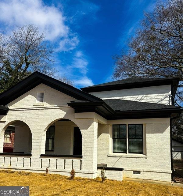 rear view of property featuring brick siding and covered porch