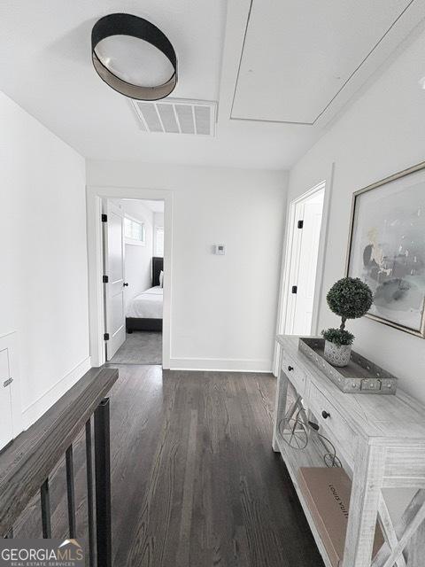 hallway featuring attic access, wood finished floors, and baseboards