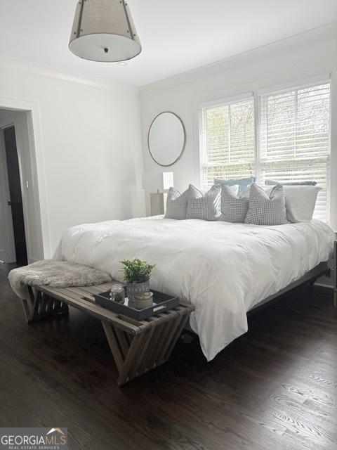 bedroom featuring ornamental molding and wood finished floors