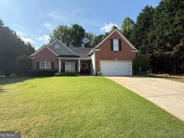 view of front of home with brick siding, a garage, driveway, and a front yard
