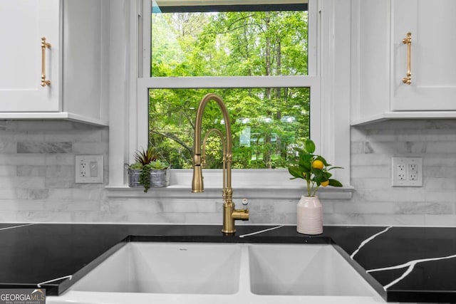 interior details with a sink, white cabinets, and tasteful backsplash
