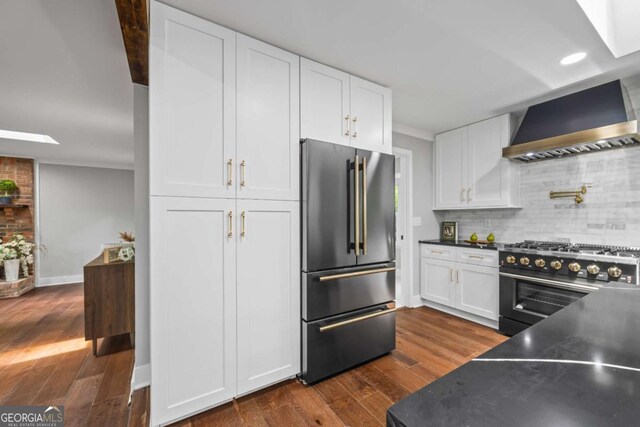 125 Terrell Dr, Athens, GA 30606 - kitchen with high end appliances, wall chimney range hood, white cabinets, dark wood-style flooring, and tasteful backsplash