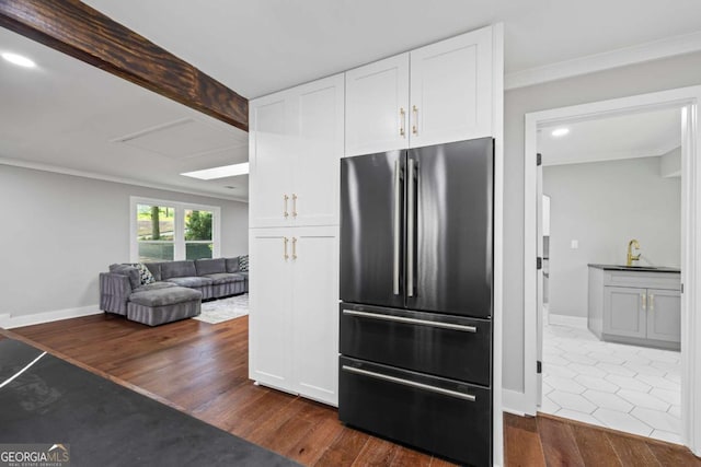 kitchen with crown molding, dark wood-style flooring, high quality fridge, white cabinets, and a sink