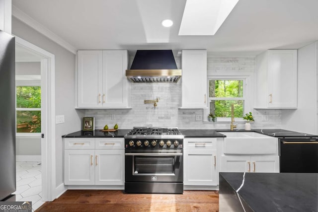 kitchen with dark countertops, appliances with stainless steel finishes, plenty of natural light, and wall chimney exhaust hood