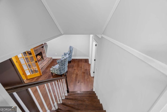 stairs featuring vaulted ceiling, hardwood / wood-style flooring, and a fireplace