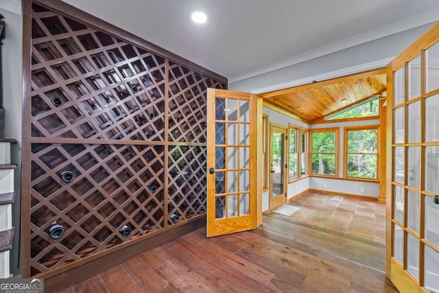 wine area with crown molding, wood finished floors, baseboards, lofted ceiling, and recessed lighting