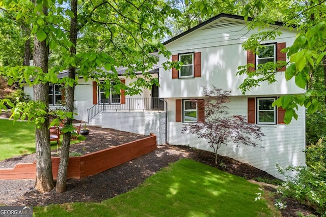 split level home featuring a front yard and brick siding