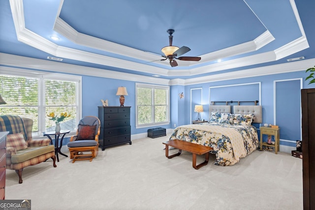carpeted bedroom with a ceiling fan, a tray ceiling, visible vents, and ornamental molding