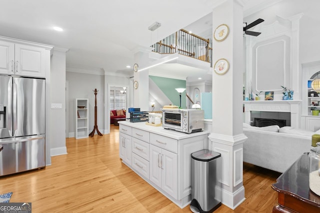 kitchen featuring crown molding, a toaster, open floor plan, white cabinetry, and stainless steel fridge with ice dispenser