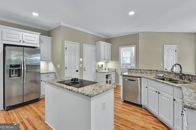 kitchen with crown molding, white cabinets, a sink, light wood finished floors, and stainless steel appliances