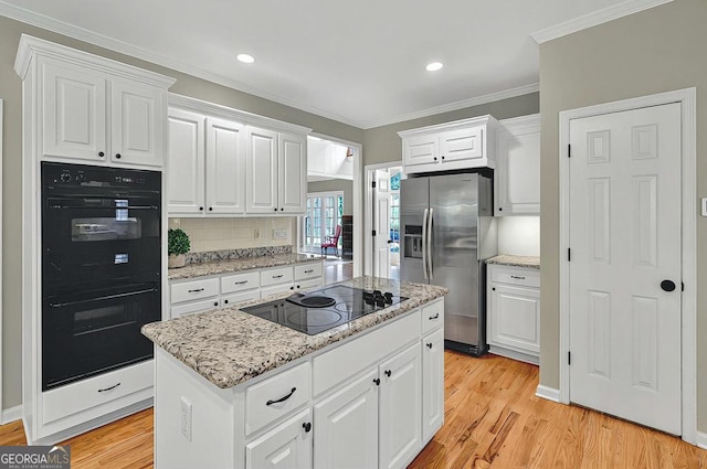 kitchen with black appliances, light wood-type flooring, and white cabinetry