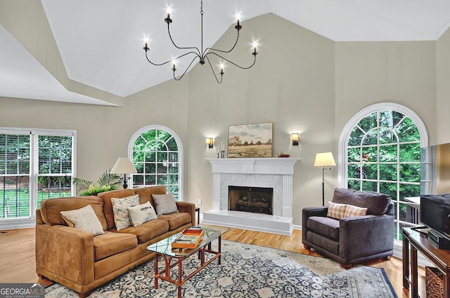 living room featuring plenty of natural light, wood finished floors, a notable chandelier, and high vaulted ceiling