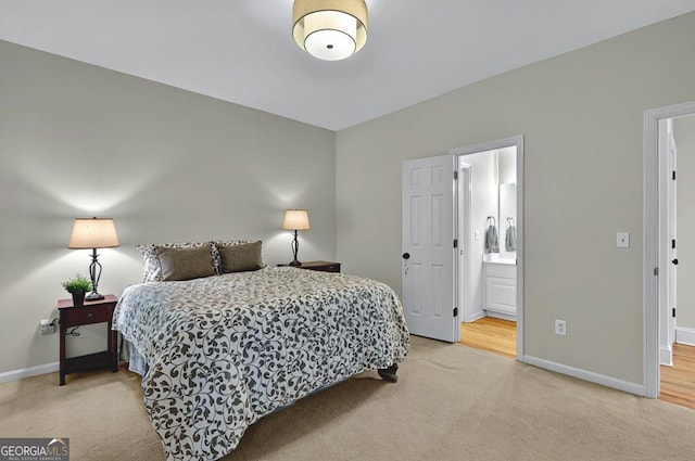 bedroom featuring baseboards, light carpet, and ensuite bathroom