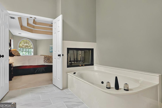 full bathroom with a garden tub, visible vents, a raised ceiling, connected bathroom, and a skylight