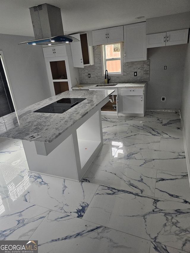 kitchen with light stone counters, a sink, black electric cooktop, white cabinetry, and island exhaust hood