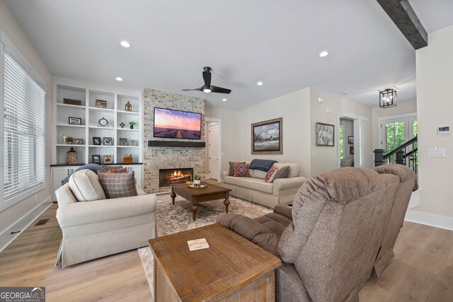 living area with light wood-type flooring, recessed lighting, a brick fireplace, and ceiling fan