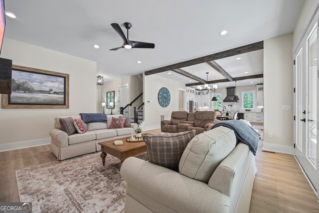 living room featuring baseboards, stairway, recessed lighting, light wood finished floors, and ceiling fan with notable chandelier