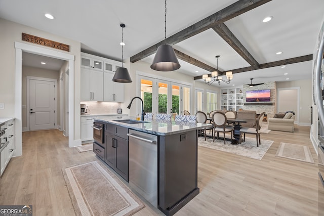 kitchen with stainless steel dishwasher, a sink, white cabinets, and light wood-type flooring