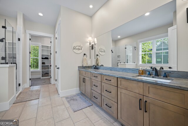 bathroom featuring a sink, a walk in closet, a shower stall, and double vanity