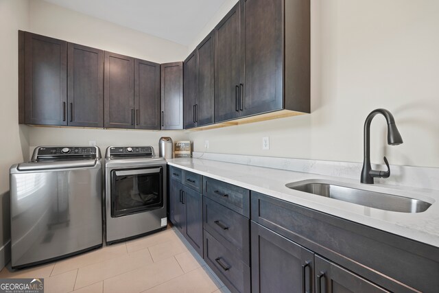 clothes washing area featuring a sink, light tile patterned floors, cabinet space, and washer and dryer