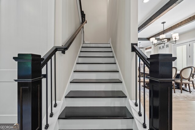 stairway with beam ceiling, recessed lighting, wood finished floors, and a chandelier