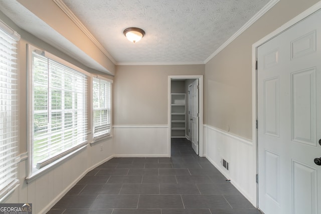 2814 Brackenwood Dr, Snellville, GA 30039 - unfurnished bedroom with wainscoting, a walk in closet, crown molding, dark tile patterned floors, and a textured ceiling