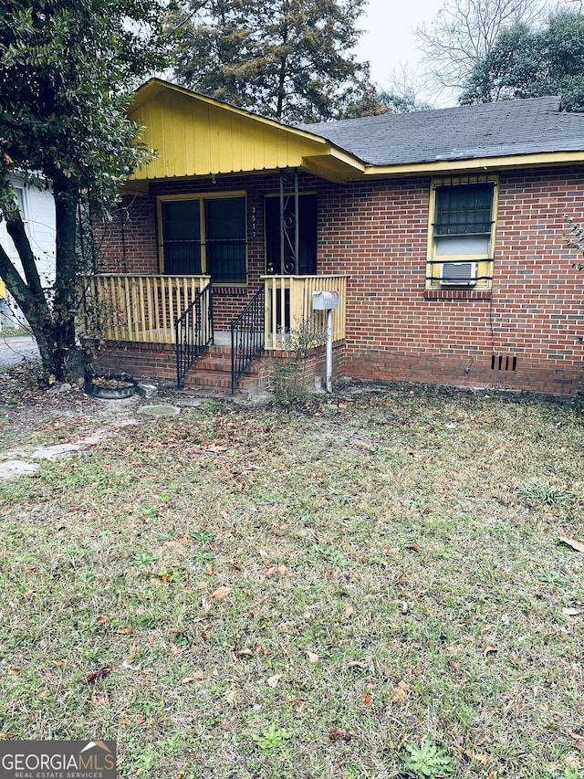 view of front of home featuring covered porch, brick siding, and a front yard