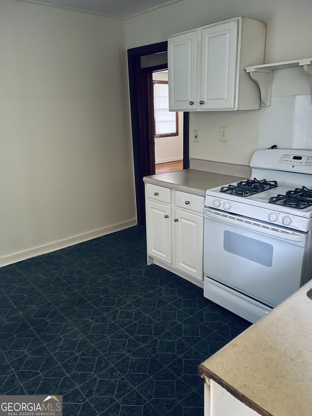 kitchen featuring light countertops, white cabinetry, and gas range gas stove