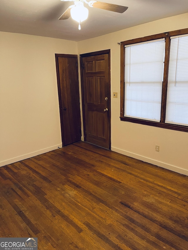 unfurnished room featuring ceiling fan, dark wood-style floors, and baseboards