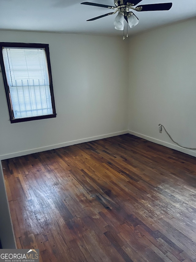 empty room featuring baseboards, a ceiling fan, and dark wood-style floors