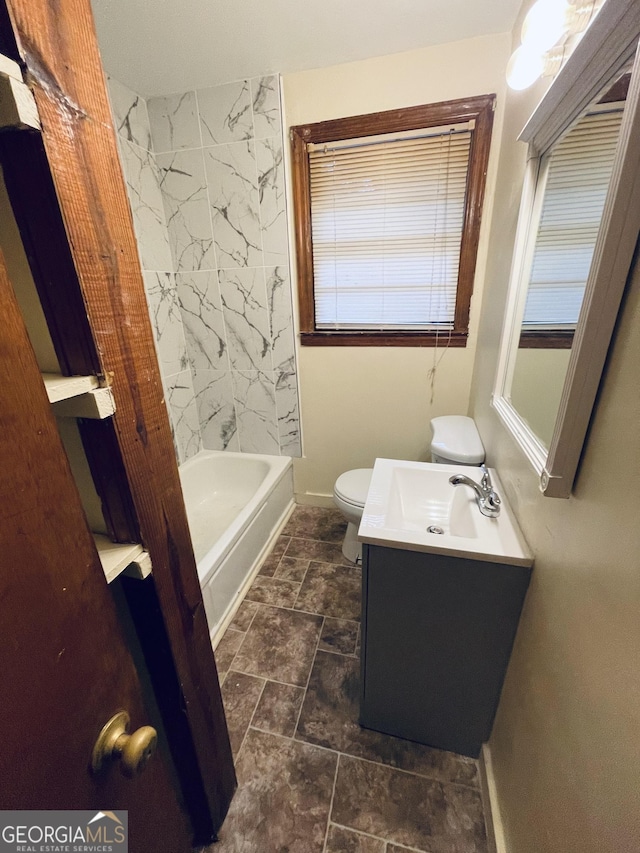 bathroom with toilet, baseboards, stone finish flooring, and vanity