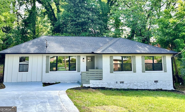 view of front of house featuring brick siding, roof with shingles, a front yard, and crawl space