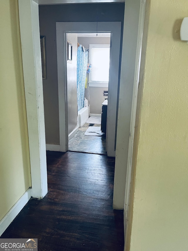 corridor with baseboards and wood finished floors