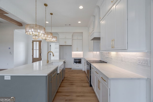 kitchen featuring stainless steel electric range oven, an inviting chandelier, a sink, light wood-style floors, and decorative backsplash