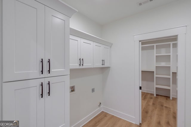 laundry area featuring hookup for an electric dryer, visible vents, cabinet space, baseboards, and light wood-style flooring