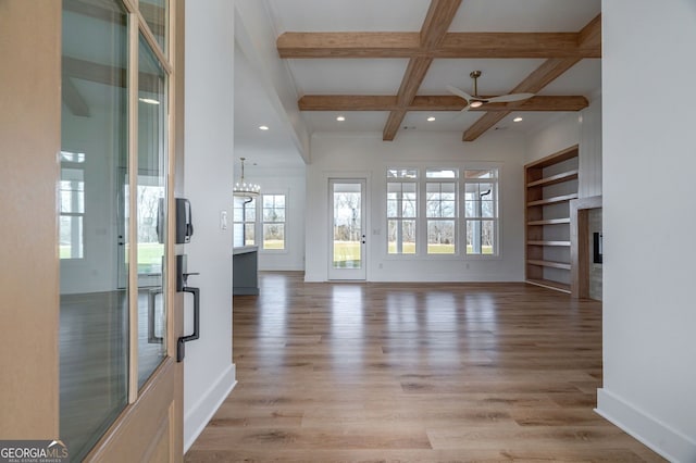 unfurnished living room featuring light wood-style floors, a glass covered fireplace, recessed lighting, baseboards, and beamed ceiling