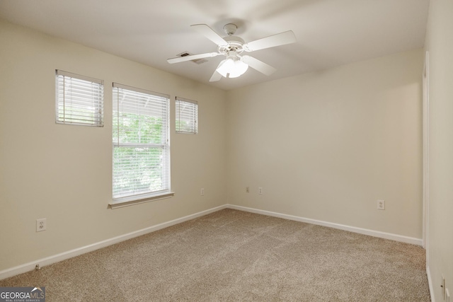 carpeted spare room featuring a ceiling fan and baseboards
