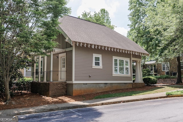 view of property exterior featuring a porch, crawl space, board and batten siding, and a shingled roof