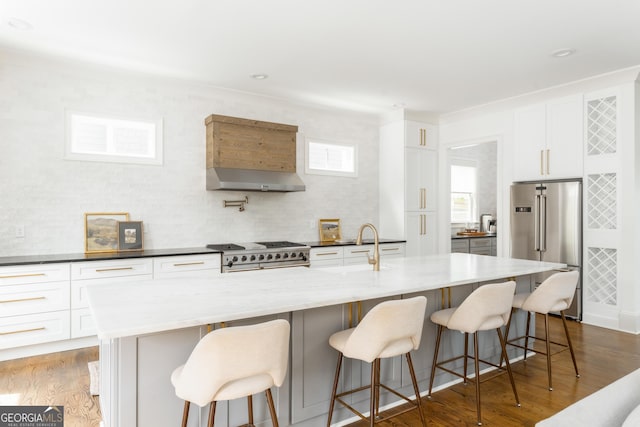 kitchen featuring a sink, wood finished floors, high quality appliances, and white cabinetry